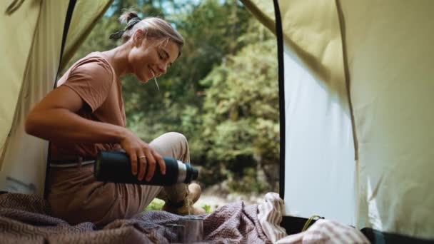 Усміхнена Туристична Жінка Вливає Воду Чашку Сидячи Наметі Горах — стокове відео