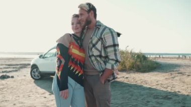 Sarışın güzel bir çift birbirine bakıyor ve açık deniz kenarında sarılıyorlar.