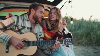 Gitar çalan ve arabanın bagajında şarkı söyleyen komik sarışın çift.