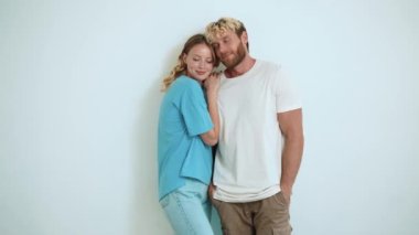 Beyaz stüdyoda birbirine bakan pozitif sarışın genç çift.