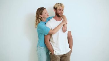 Mutlu sarışın genç çift beyaz stüdyoda sarılıyor.