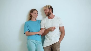 Gülümseyen sarışın genç çift beyaz stüdyoda konuşuyor.