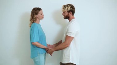 Beyaz stüdyoda el ele tutuşan güzel sarışın genç bir çift.