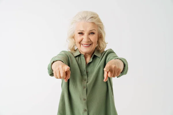 灰色的老妇人 身穿衬衫 微笑着用手指指着白色背景上的相机 — 图库照片
