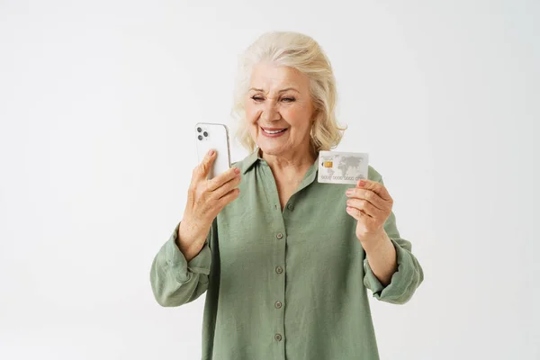 白い背景に隔離された携帯電話やクレジットカードを示しながら笑顔グレーシニア女性 — ストック写真
