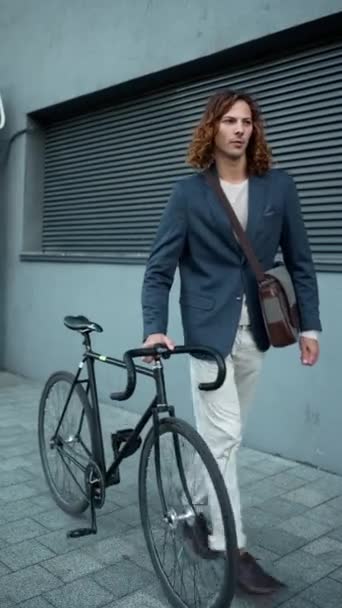 Hombre Pelo Rizado Serio Con Chaqueta Caminando Con Una Bicicleta — Vídeo de stock