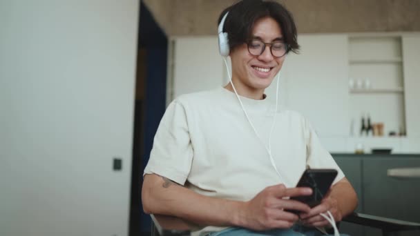 Alegre Jovem Asiático Morena Homem Digitando Telefone Ouvir Música Fones — Vídeo de Stock