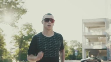 Gözlüklü kendine güveni tam bir sporcu yolda koşuyor.