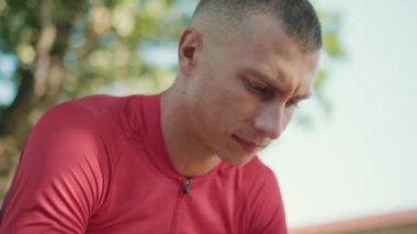 Parktaki bankta oturan ciddi bir sporcu.