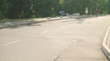 Kasklı ve gözlüklü güçlü bir sporcu dışarıda bisiklet sürüyor.