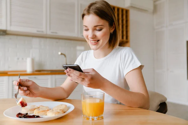 Mosolygó Fiatal Egészséges Reggeli Konyhában Otthon Kezében Mobiltelefon — Stock Fotó