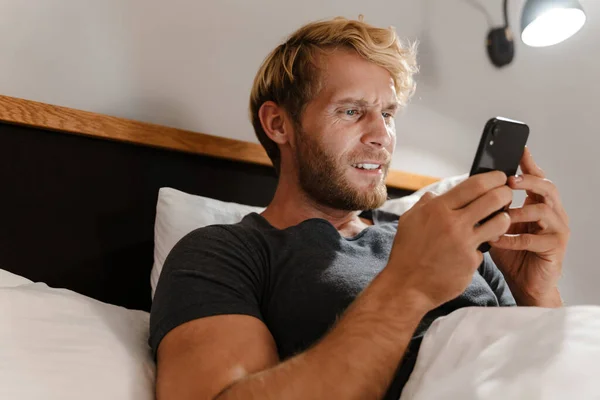 Rubia Barbudo Hombre Usando Teléfono Móvil Mientras Está Acostado Cama — Foto de Stock