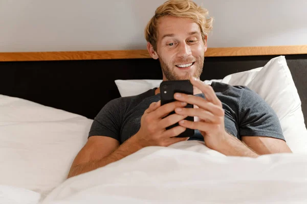 Sarışın Sakallı Adam Evde Yatarken Cep Telefonu Kullanıyor — Stok fotoğraf