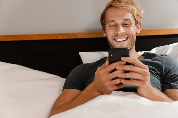 Блондинка Бородатий Чоловік Використовує Мобільний Телефон Лежачи Ліжку Вдома — стокове фото