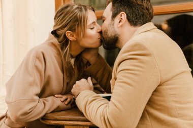 Kafede kahve içerken öpüşen beyaz romantik çift.