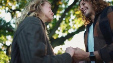 Parkta konuşan ve el ele tutuşan mutlu genç çift.