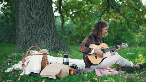 Positiv Lockig Man Spelar Gitarr Filt Vid Picknick Parken — Stockvideo