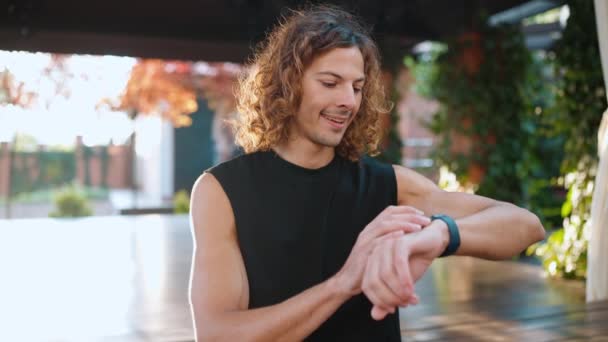 Szczęśliwy Kręcone Włosy Sportowy Człowiek Patrząc Smartwatch Machając Ręką Przed — Wideo stockowe