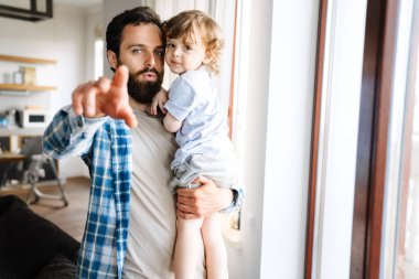 Gülümseyen orta yaşlı bir baba oğlunu kucağında tutuyor.