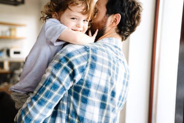 Gülümseyen orta yaşlı bir baba oğlunu kucağında tutuyor.