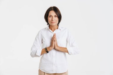 Olgun esmer kadın, beyaz arka planda el ele tutuşurken poz veriyor.