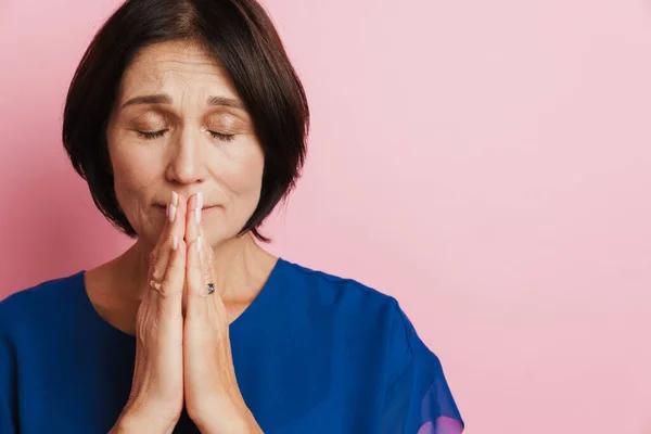 Зрелая Женщина Делает Молитвенный Жест Позируя Камеру Изолированы Розовом Фоне — стоковое фото
