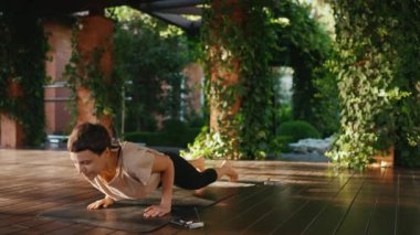 Ciddi kısa saçlı kadın dışarıda yoga egzersizi yapıyor.
