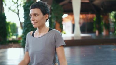 Gülümseyen kısa saçlı sporcu kadın dışarı bakıyor.