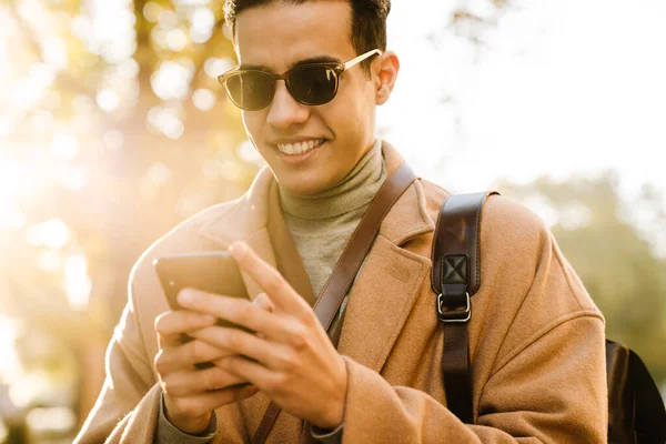 Giovane Uomo Che Indossa Cappotto Utilizzando Telefono Cellulare Mentre Cammina — Foto Stock