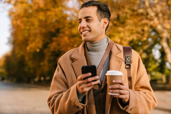 Giovane Uomo Che Indossa Cappotto Utilizzando Cellulare Bere Caffè Mentre — Foto Stock