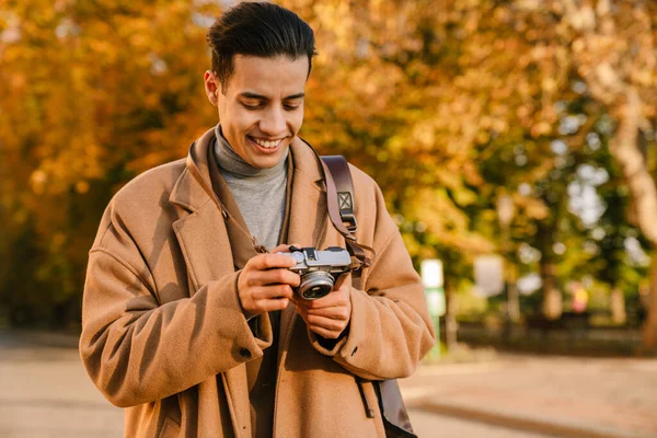 Hombre Joven Con Abrigo Tomando Fotos Cámara Retro Mientras Camina — Foto de Stock