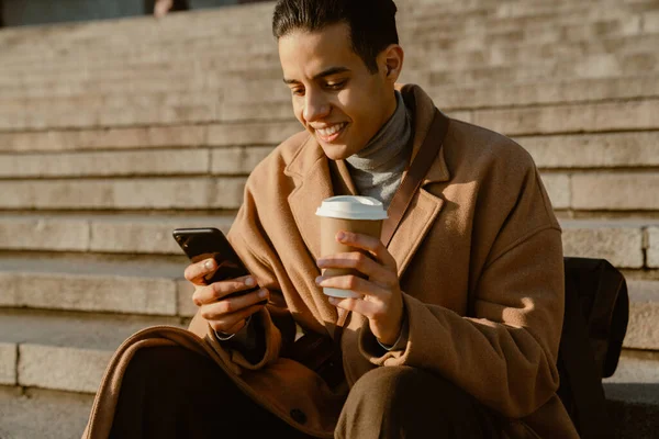 Giovane Uomo Che Indossa Cappotto Bere Caffè Utilizzando Telefono Cellulare — Foto Stock