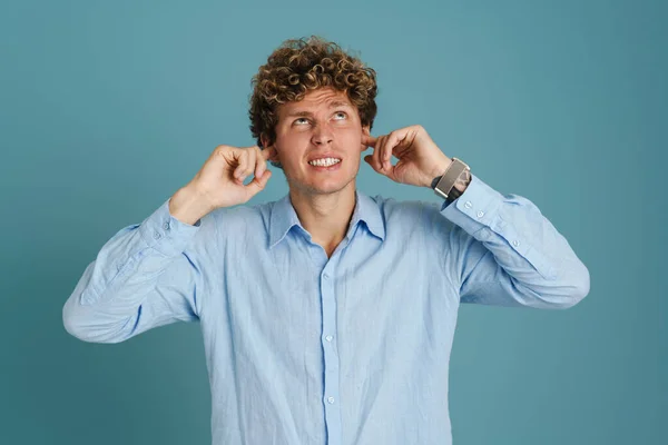 Genç Kıvırcık Adam Kaşlarını Çatıyor Kulaklarını Tıkıyor — Stok fotoğraf