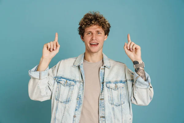 Ung Lockig Man Bär Jacka Ler Och Pekar Finger Uppåt — Stockfoto