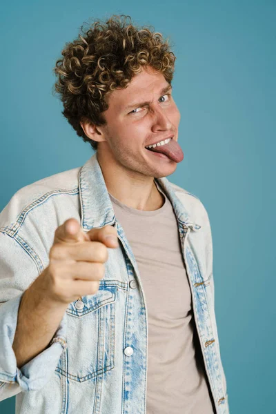 Young Man Showing His Tongue Pointing Finger Camera Isolated Blue — Stock Photo, Image