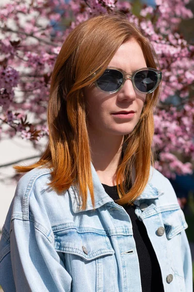 Young Red Hair Woman Sunglasses Denim Jacket Front Blossoming Peach — Zdjęcie stockowe