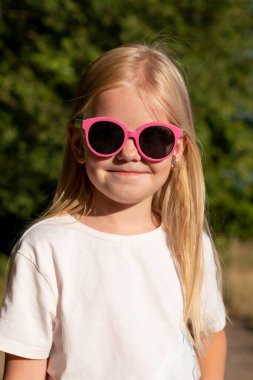 Cute  little girl with blonde hair in pink sunglasses