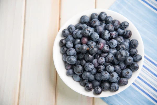 Fresh blueberries ion white plate on kitchen table — Stock Photo, Image