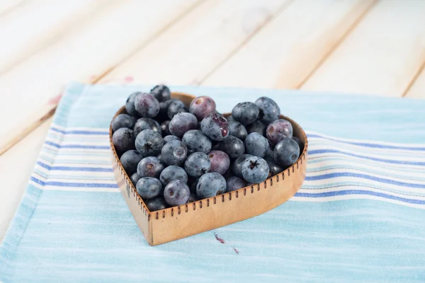 Fresh blueberries in heart shape basket on kitchen table — Stock Photo, Image