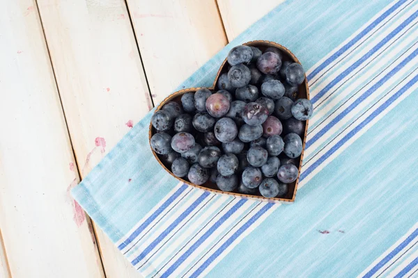 Frische Blaubeeren in Herzform Korb auf Küchentisch — Stockfoto