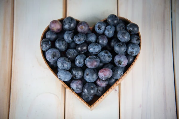 Fresh blueberries in hearth shape basket on kitchen table — Stock Photo, Image