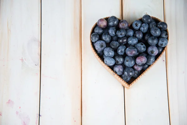 Fresh blueberries in heart shape basket on kitchen table — Stock Photo, Image