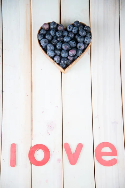 Frische Blaubeeren in Herzform Korb auf Küchentisch — Stockfoto