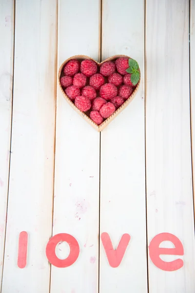 Frambuesas frescas en forma de corazón cesta en la mesa de la cocina — Foto de Stock