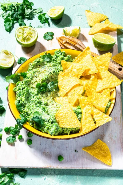ナチョスと緑のエンドウ豆のグアカモーレ アボカド代替健康的なパーティー食品 — ストック写真