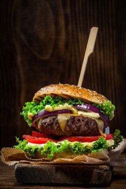 Ahşap arka planda salata ve soslu restoran burgeri..