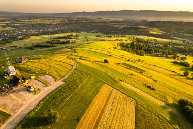 Yaz gündoğumunda Tatras dağlarındaki yuvarlanan tepelerde tarım manzarası.