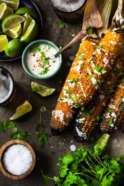 Taze otlar, limon, bira ve salsa sosuyla ızgara mısır koçanı yemek..