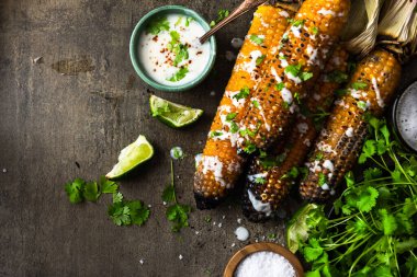 Taze bitkilerle ızgara mısır koçanı, limon, bira ve tuz, taş masada servis edilir.. .