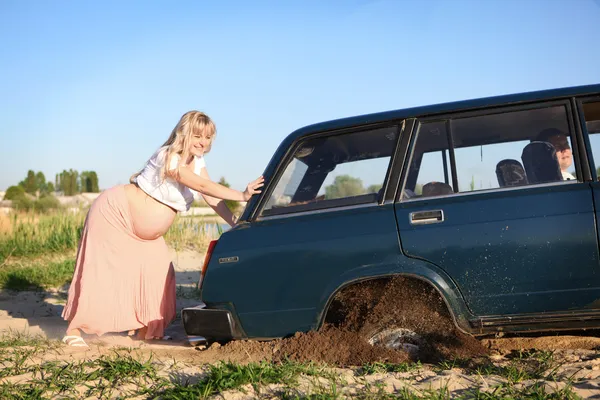 Pregnant woman pushing car — Stock Photo, Image